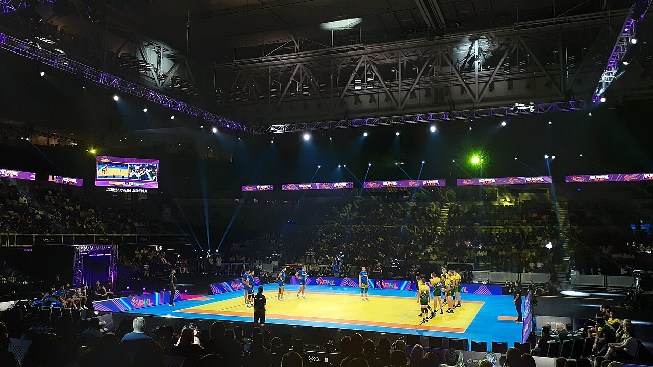 Raider reaching for the bonus line as four defenders close in during a Pro Kabaddi match